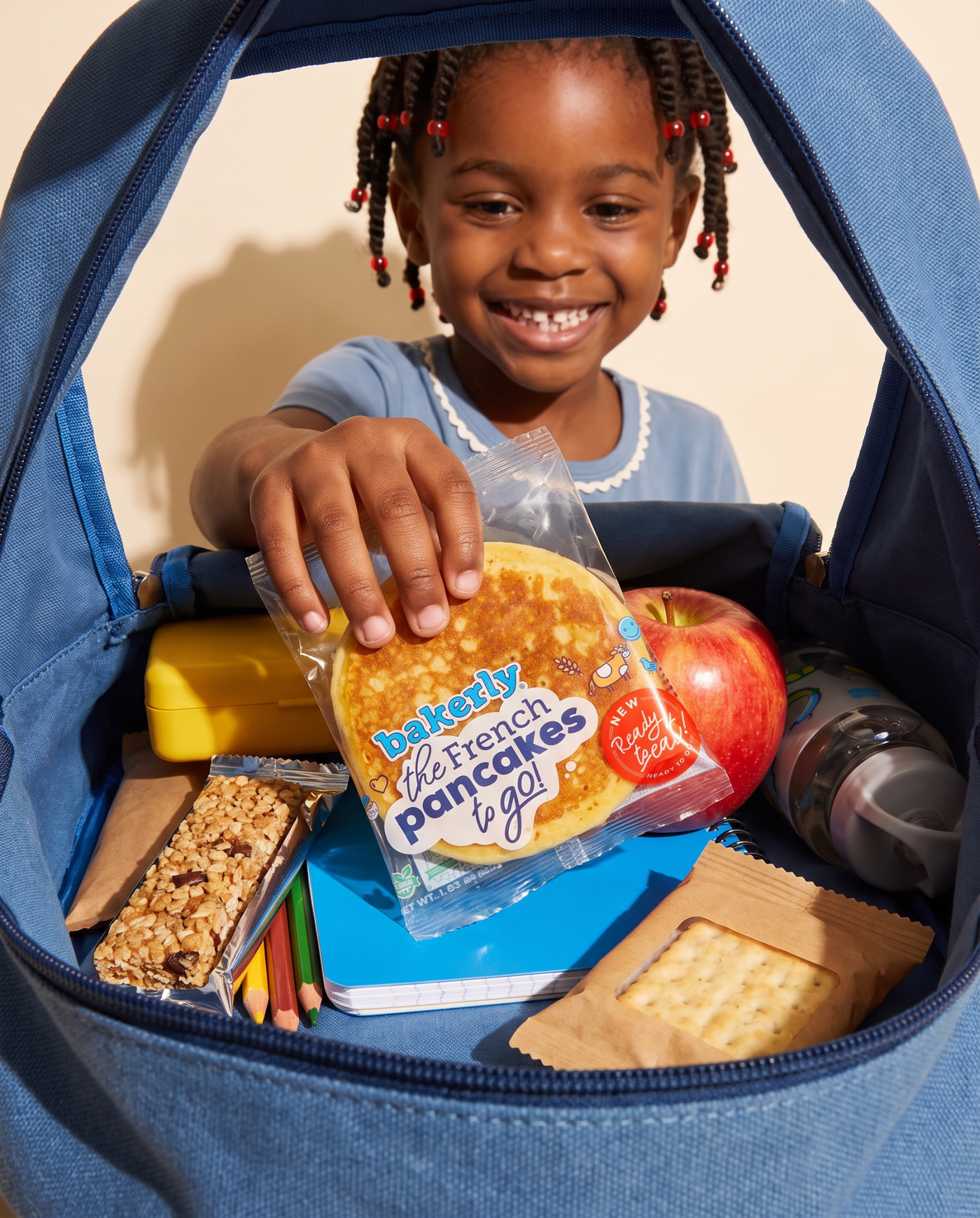 Smiling girl choosing bakerly French pancakes from her backpack
