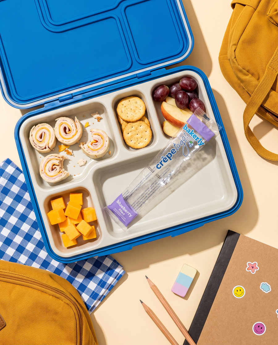 blue lunchbox with crepe pinwheels and an individually wrapped bakerly blueberry crepe