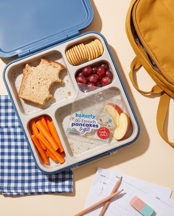 blue lunchbox with sandwich, carrots, fruit, crackers, and a bakerly French pancake