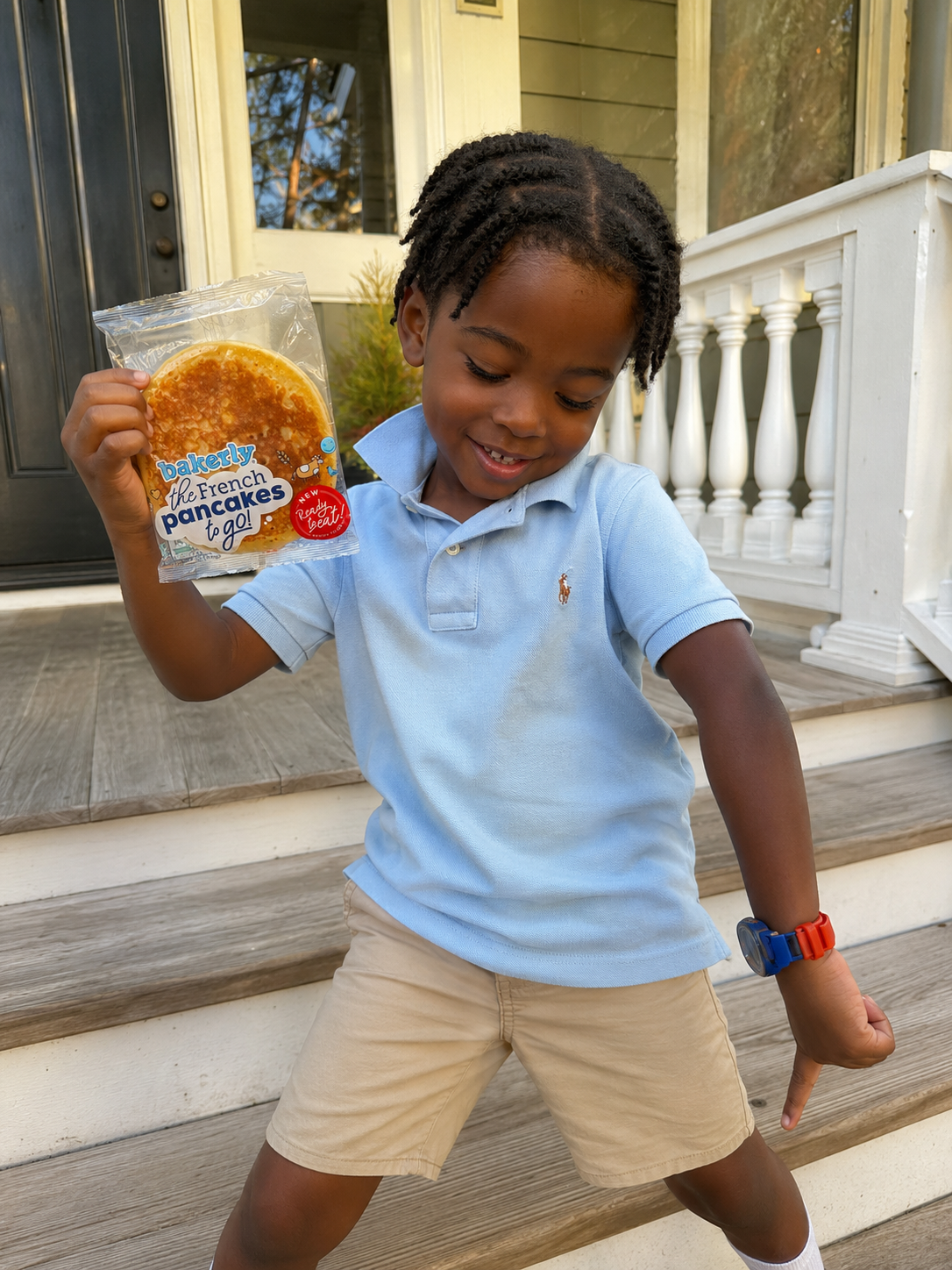 Boy holding bakerly French pancakes on the front steps